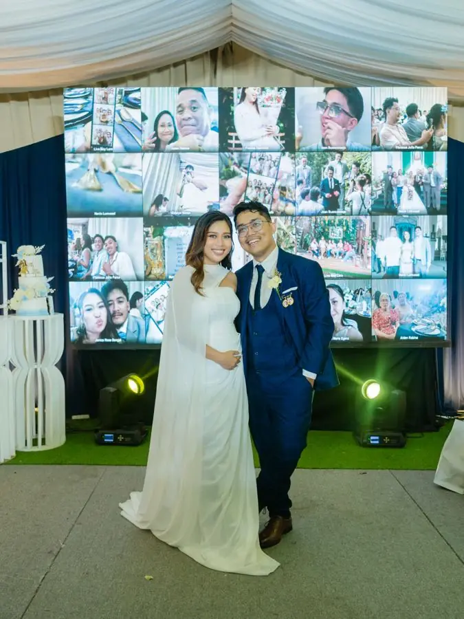 The couple in front of the big screen of guest photos
