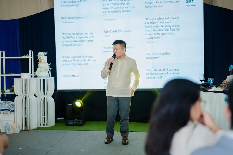 A guest giving a speech in front of the well wishes wall